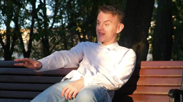 Cheerful man with signs of schizophrenia talking to himself in the park
