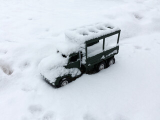 Miniature green machine is covered with snow. Winter landscape.