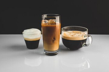 three cups of aromatic, fresh coffee with white, milk froth, on a simple black and white background