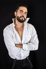 Handsome seductive man with open shirt showing chest and crossed arms. Attractive stylish bearded man in formal wear. Medium shot. Black background.