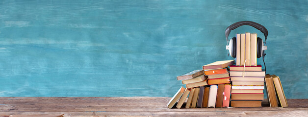 audio book concept with large heap of books and vintage headphones, good copy space