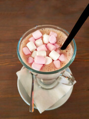 Cup of hot cocoa with pink and white marshmallows on the wooden table. Cozy autumn or winter concept.
