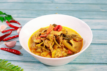 Thai food is called Kaeng The Po. Morning glory pork belly in a white cup on a blue wooden floor.