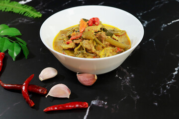 Thai food is known as Kaeng The Po, a three-tiered pork slug in a white cup on a black marble floor, a view in the middle of the top.