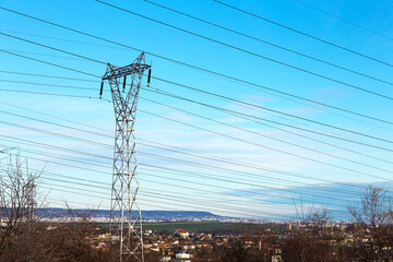High voltage lines and power pylons in a flat and green agricultural landscape on a sunny day with...
