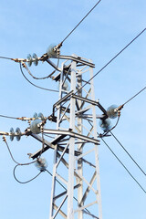 High voltage lines and power pylons in a flat and green agricultural landscape on a sunny day with cirrus clouds in the blue sky. Pylon and transmission power line