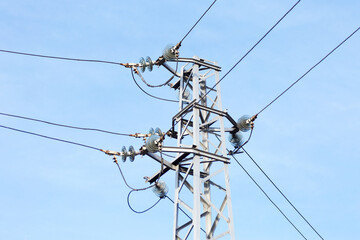 High voltage lines and power pylons in a flat and green agricultural landscape on a sunny day with cirrus clouds in the blue sky. Pylon and transmission power line