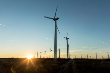 Obraz premium Wind Turbines at Dusk. Landscape sunset with windmills. Renewal source of electricity. Wind turbines field new technology for clean energy on mountain, sunset view with colorful twilight on sky