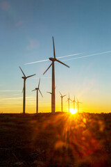 Obraz premium Wind Turbines at Dusk. Landscape sunset with windmills. Renewal source of electricity. Wind turbines field new technology for clean energy on mountain, sunset view with colorful twilight on sky