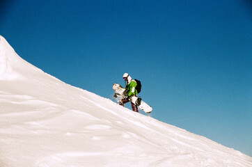 snowboarder climbs the slope with a snowboard