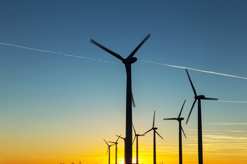 Fototapeta premium Wind Turbines at Dusk. Landscape sunset with windmills. Renewal source of electricity. Wind turbines field new technology for clean energy on mountain, sunset view with colorful twilight on sky