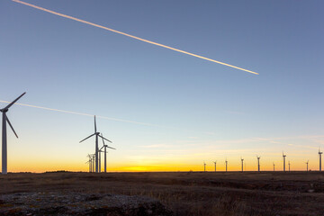 Obraz premium Wind Turbines at Dusk. Landscape sunset with windmills. Renewal source of electricity. Wind turbines field new technology for clean energy on mountain, sunset view with colorful twilight on sky