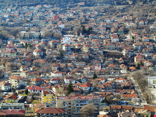 Fototapeta na wymiar View of the roofs of red tiles from a bird's eye view. Picturesque bright roofs landscape of a small town in a mountain valley. Traditional tiled roof of a European city, Bulgaria.