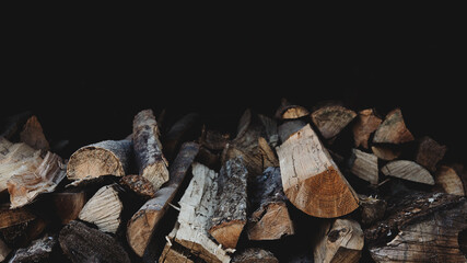 アウトドアイメージ素材：木材・焚き火・キャンプファイア・バーベキュー用の薪（横長・黒背景・コピースペース付）