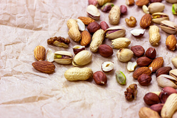 Different nuts: almonds, pistachios, peanuts, hazelnuts heap on light background.