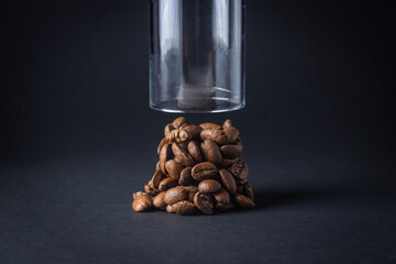 Coffee beans on a black background. Coffee beans in a small pile, glass on top