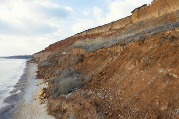 Panoramic view bird's-eye view. Mountain landslide in an environmentally hazardous area. Large cracks in the ground, the descent of layers of dirt road. Deadly risk of collapse of the soil on coast