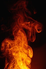 Fototapeta premium Orange smoke on a dark background. Intricate swirls of colored smoke. An abstract imitation of night flames.
