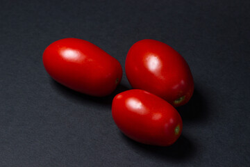 Tomatoes on a black background. Three red tomatoes lie next to each other