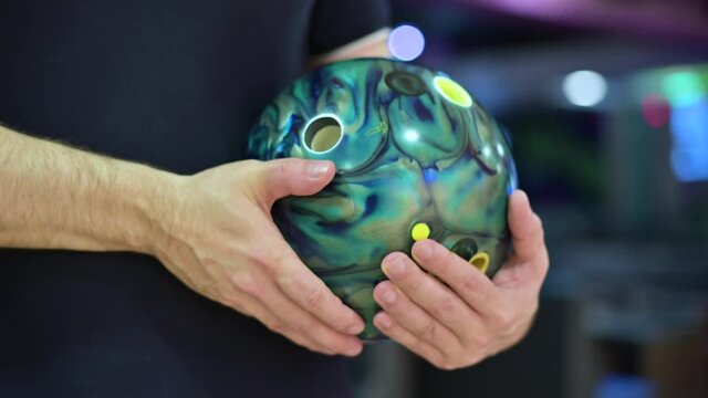 Close-up of a bowling ball in the player's hand. The camera zooms out and shows the player