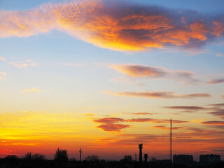 Dark, clear silhouettes of the roofs of houses with chimneys and pipes in the rays of the setting sun. Sunset in the city. Silhouette City landscape in the backlight of the sunset.