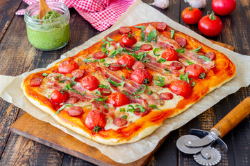 Pizza with bacon, sausage, mozzarella, tomatoes and basil. Italian cuisine. Recipe.