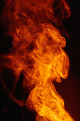 Orange smoke on a dark background. Intricate swirls of colored smoke. An abstract imitation of night flames.