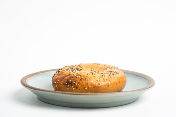 A Freshly Baked Single Bagel On A Ceramic Plate