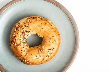 A Freshly Baked Single Bagel On A Ceramic Plate