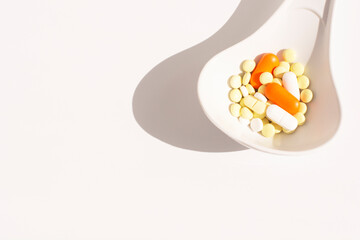 multi-colored pills in a white spoon. Medicines to treat the disease.