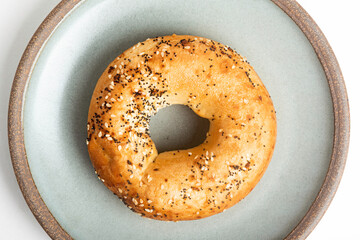 A Freshly Baked Single Bagel On A Ceramic Plate