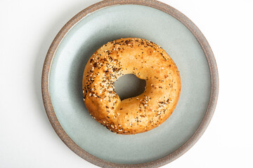 A Freshly Baked Single Bagel On A Ceramic Plate