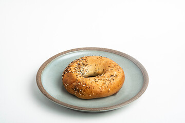 A Freshly Baked Single Bagel On A Ceramic Plate