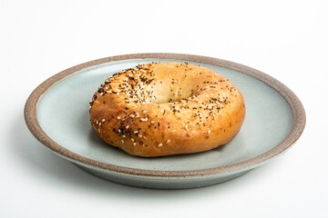 A Freshly Baked Single Bagel On A Ceramic Plate