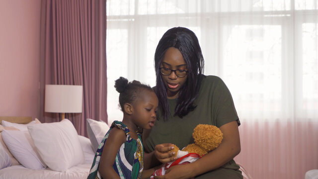 Portrait Of Smiling Business Black African American Woman, A Mom With Her Daughter Playing A Bear Doll Toy In Family Relationship Concept On Pink Background. A Black Kid Toddler Girl With Her Parent.