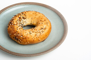 A Freshly Baked Single Bagel On A Ceramic Plate