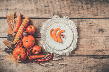 Autumn table setting, menu composition, vintage cutlery, sliced pumpkin. Thanksgiving food, healthy and fresh, top view, flat lay, copy space. Fallen leaves, fruits, vegetables, wooden table.