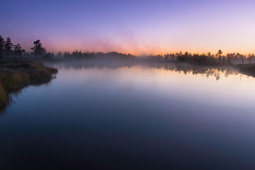 Fototapeta na wymiar Twilight at sunrise over calm lake in autumn morning
