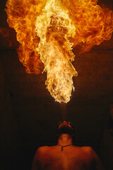 Male fakir blowing out fire in an abandoned building at night. Fire performer blowing out fire...