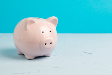 pink piggy bank on blue background with copy space
