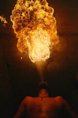 Male fakir blowing out fire in an abandoned building at night. Fire performer blowing out fire...