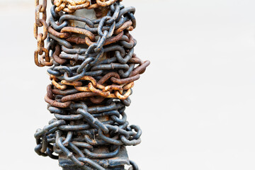 An old rusty chain is wound in rings on a vertical support.