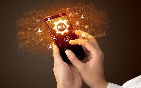 Female hand holding smartphone with RCS abbreviation, modern technology concept