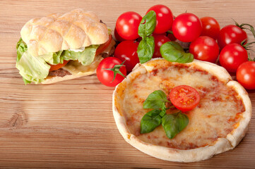 Closeup of pizza with hamburger, tomatoes, cheese and basil on wooden background