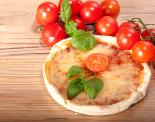 Closeup of pizza with tomatoes, cheese and basil on wooden background