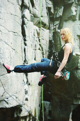 Female rock climber abseiling down rock face