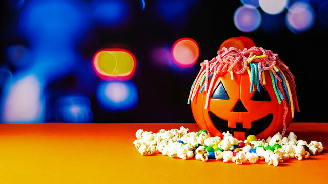 Calabaza de halloween llena gominolas formando el  pelo y con palomitas. 