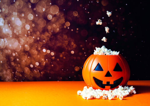 Calabaza de halloween llena palomitas. Varias de ellas levitando