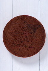 Round chocolate sponge cake on a light wooden background