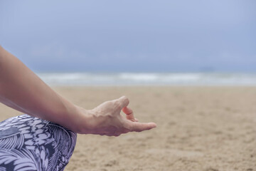hand of woman doing lotus yoga pose  on beach, copy space